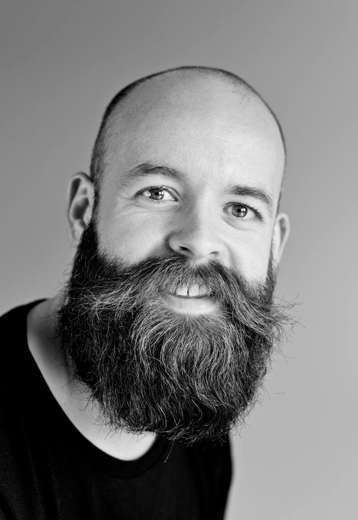 a black and white photo of a middle-aged man with a bald head and a huge long black beard
